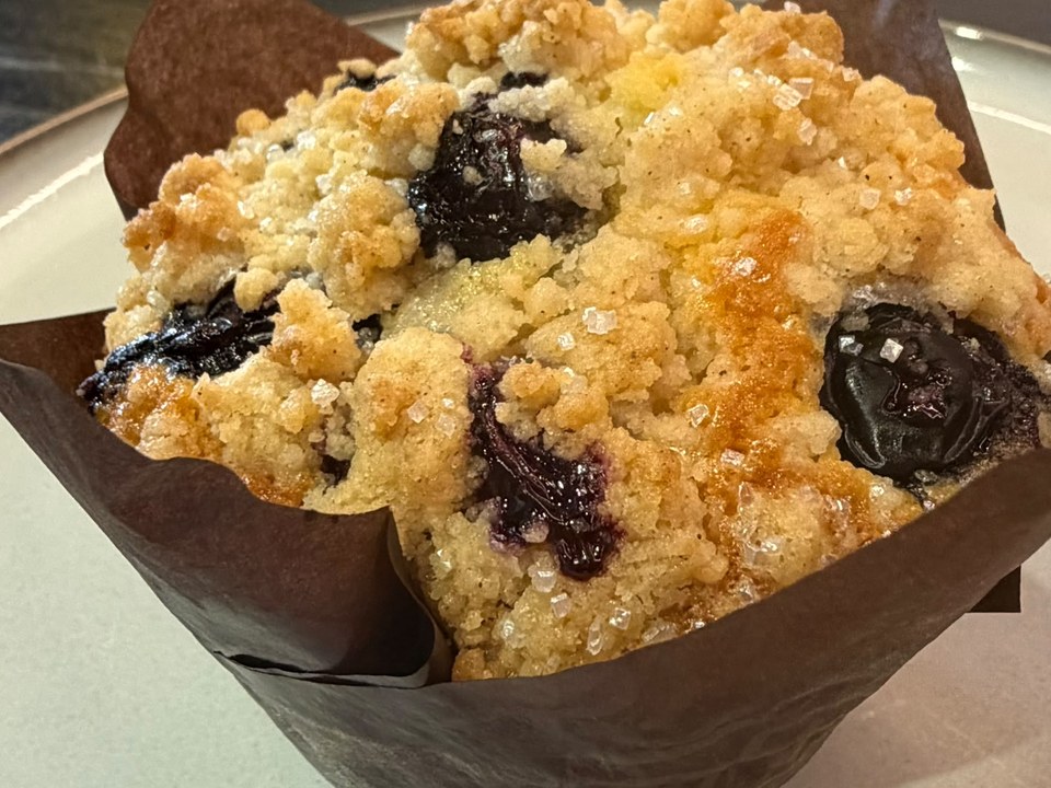 Blue Bloom Muffin — blueberry muffin with a golden crumble topping and sugar crystals, in a brown tulip wrapper